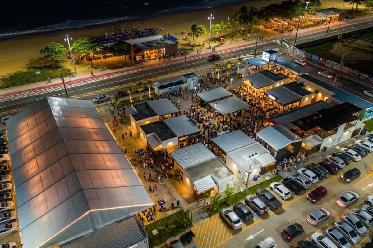 Vista aérea noturna do Itapuã Gran Park, com a tenda, a área gastronômica e a orla ao fundo